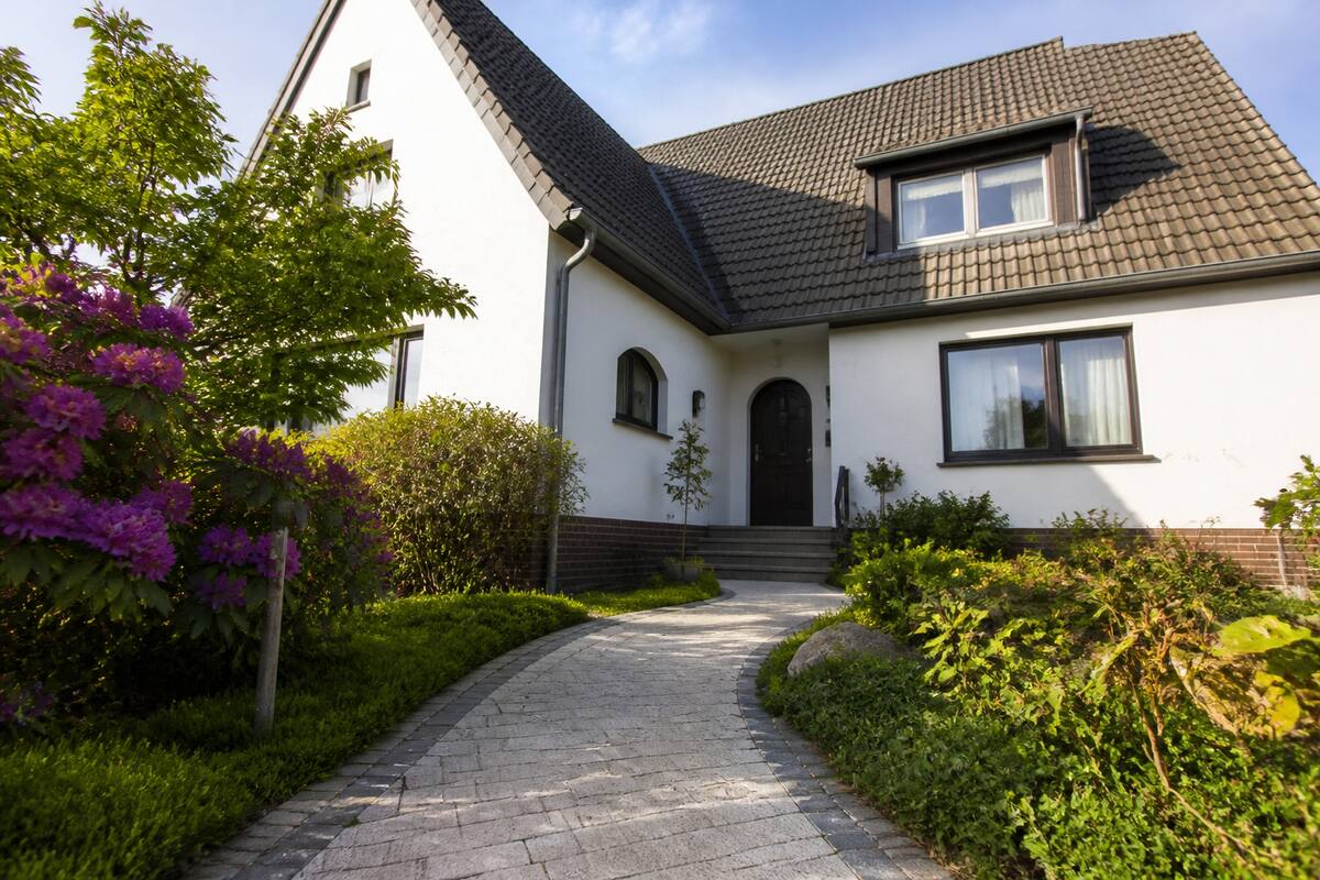 Een realistisch Duits woonhuis met tuin en oprijpad, passend bij het onderwerp huis kopen in Duitsland